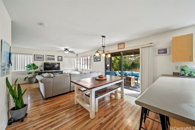 dining area featuring light wood-type flooring and ceiling fan with notable chandelier