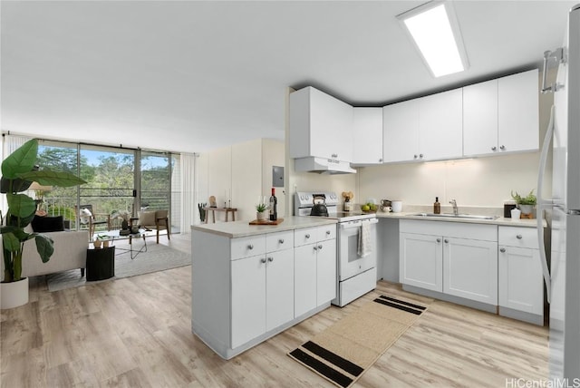 kitchen with white appliances, a peninsula, a sink, floor to ceiling windows, and under cabinet range hood