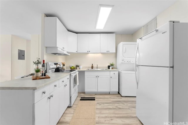 kitchen with white appliances, electric panel, a sink, light countertops, and stacked washer / drying machine