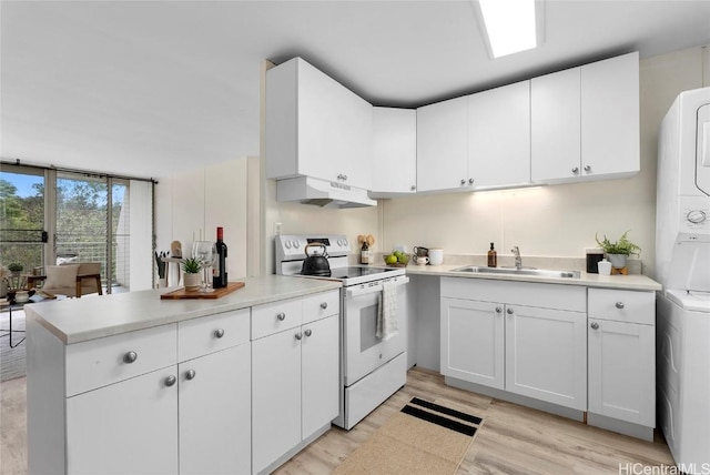 kitchen featuring under cabinet range hood, light countertops, stacked washer and clothes dryer, white electric stove, and a sink