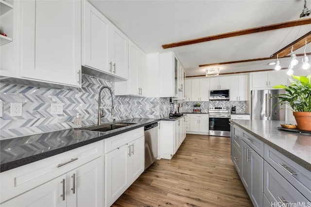 kitchen with a sink, tasteful backsplash, wood finished floors, stainless steel appliances, and white cabinets