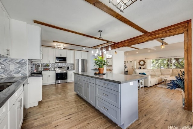 kitchen featuring beam ceiling, dark countertops, appliances with stainless steel finishes, and tasteful backsplash