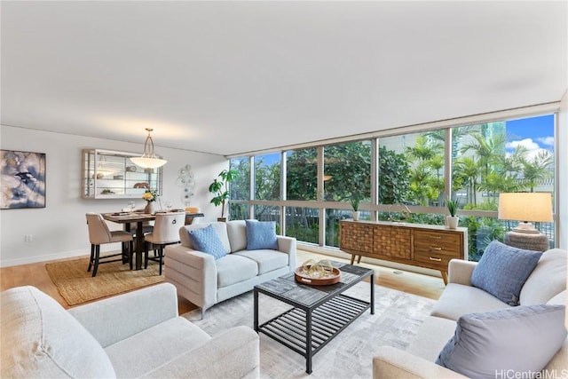 living room featuring light wood-type flooring, baseboards, and a wall of windows