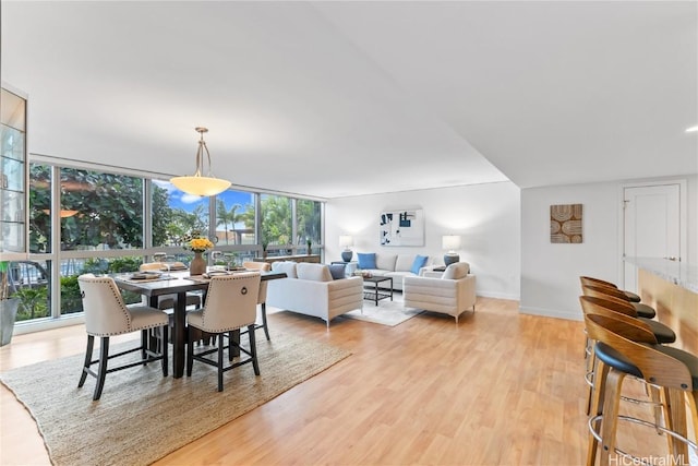 dining space with light wood-style floors, baseboards, and floor to ceiling windows