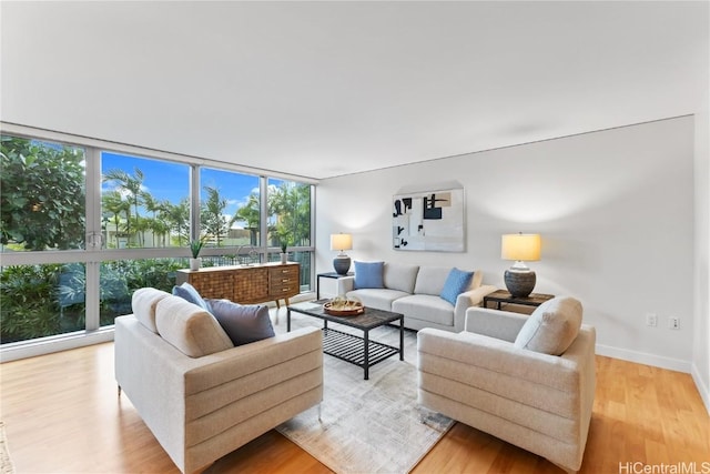 living area featuring a wall of windows, light wood-style floors, and baseboards