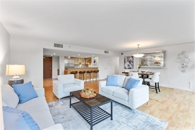 living room with baseboards, visible vents, and light wood-style floors