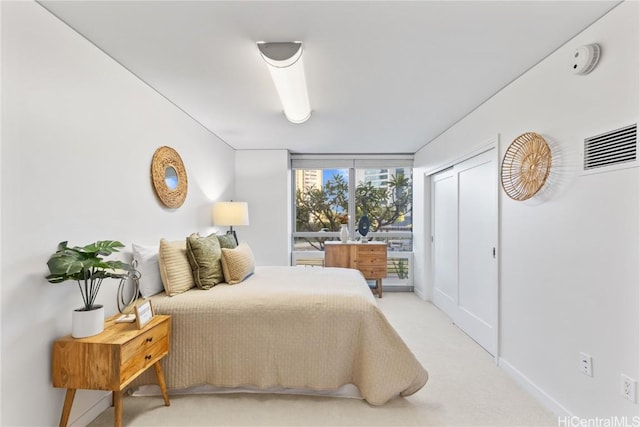 bedroom with a wall of windows, visible vents, and light colored carpet