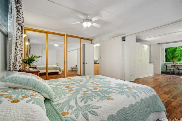 bedroom with a ceiling fan, multiple closets, and wood finished floors