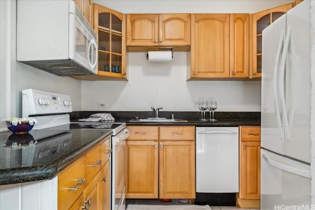 kitchen with white appliances, glass insert cabinets, dark stone counters, and a sink