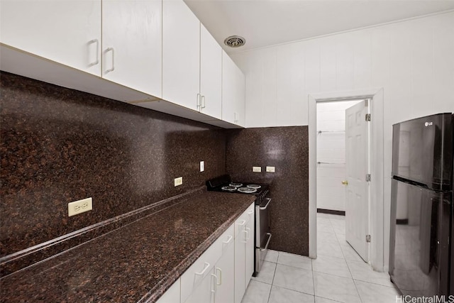 kitchen with light tile patterned floors, electric range, visible vents, white cabinets, and freestanding refrigerator