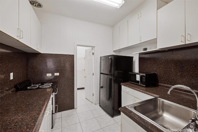 kitchen with stainless steel microwave, freestanding refrigerator, white cabinets, a sink, and range with electric cooktop