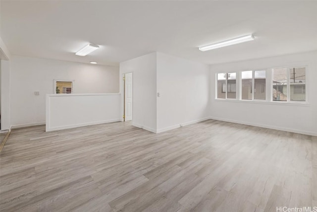 spare room with baseboards and light wood-style floors