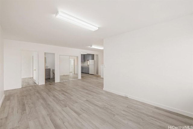 spare room featuring baseboards and light wood finished floors