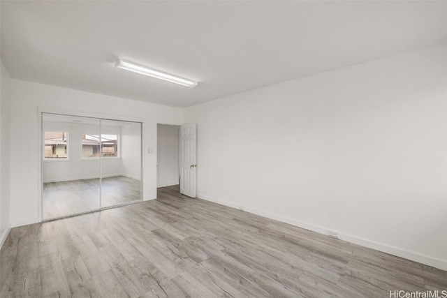 unfurnished bedroom with a closet, baseboards, and wood finished floors