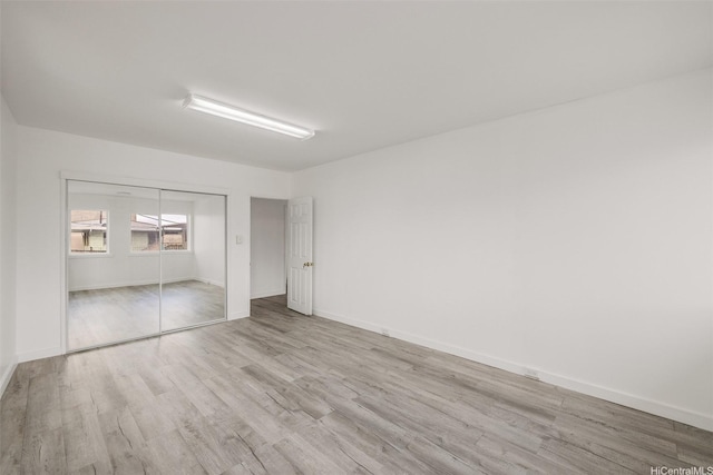 unfurnished bedroom featuring wood finished floors, a closet, and baseboards