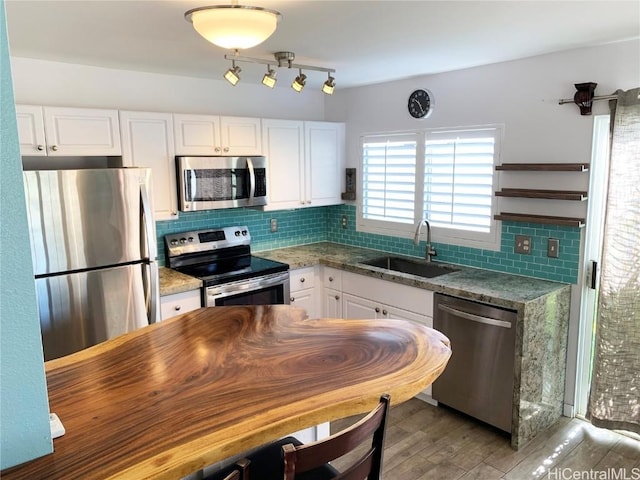 kitchen featuring decorative backsplash, appliances with stainless steel finishes, white cabinetry, a sink, and light stone countertops