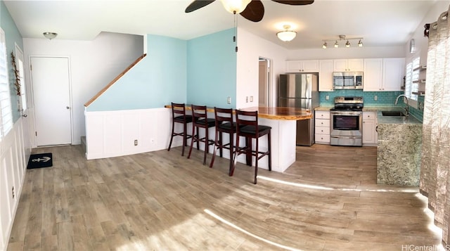 kitchen featuring appliances with stainless steel finishes, light countertops, white cabinetry, and a sink