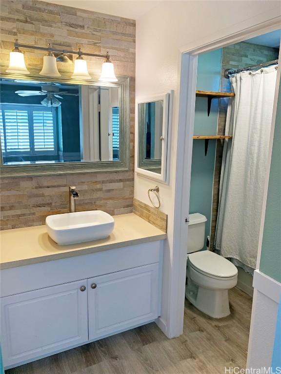 full bathroom with tasteful backsplash, vanity, toilet, and wood finished floors