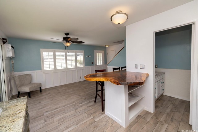 91-1016C Hoomaka St Unit 78, Ewa Beach, HI 96706 - dining space with wainscoting, a ceiling fan, light wood-style flooring, and stairs