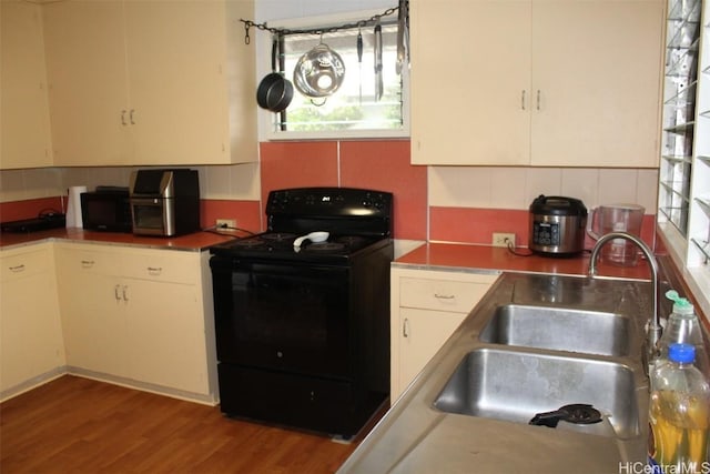 kitchen featuring tasteful backsplash, white cabinets, a sink, and black appliances