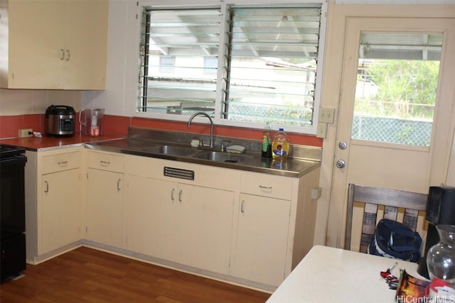 kitchen with electric range, white cabinets, dark wood-style flooring, stainless steel counters, and a sink