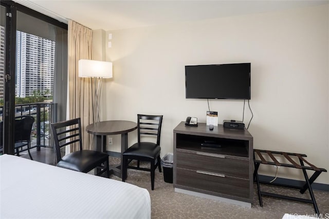 bedroom featuring carpet floors, baseboards, and a wall of windows