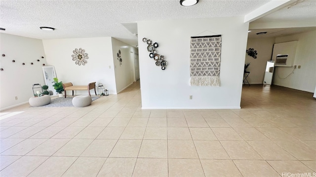 empty room with light tile patterned floors, baseboards, and a textured ceiling