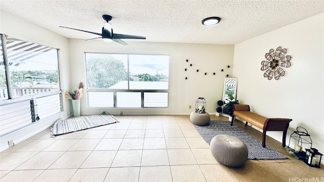 workout area featuring ceiling fan, a textured ceiling, baseboards, and tile patterned floors