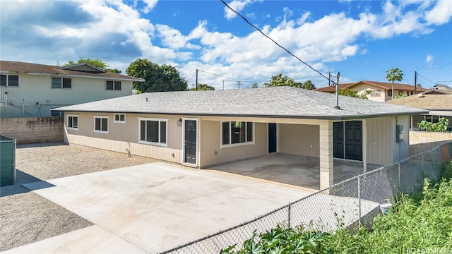 rear view of property with an attached carport, a fenced backyard, driveway, and a shingled roof