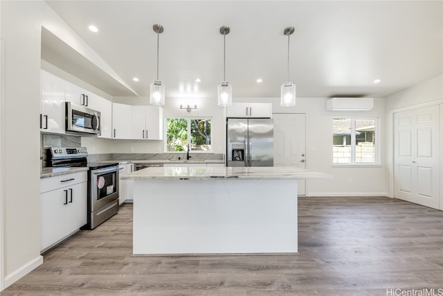 kitchen featuring a kitchen island, a healthy amount of sunlight, white cabinetry, and stainless steel appliances