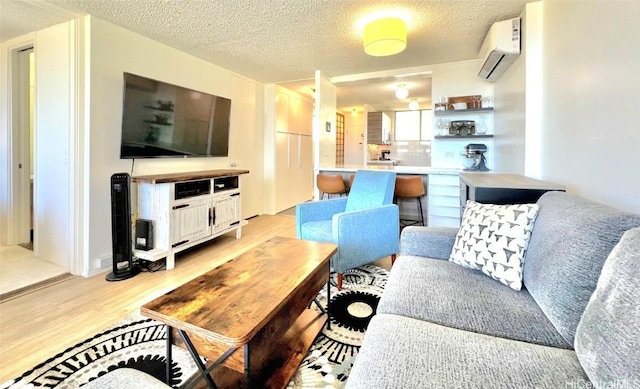 living room with light wood-type flooring, a wall unit AC, and a textured ceiling