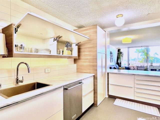 kitchen with light countertops, backsplash, white cabinetry, a sink, and dishwasher