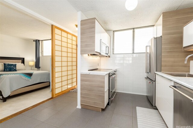1676 Ala Moana Blvd Unit 205, Honolulu, HI 96815 - kitchen with stainless steel appliances, a sink, light countertops, healthy amount of natural light, and a textured ceiling