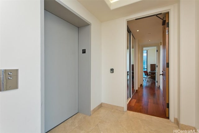 hall featuring elevator and light tile patterned flooring