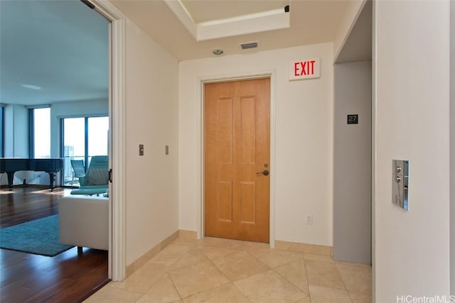 hallway with visible vents, baseboards, and light tile patterned floors