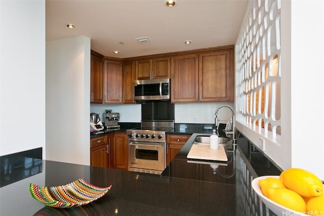 kitchen with appliances with stainless steel finishes, brown cabinetry, a sink, and recessed lighting