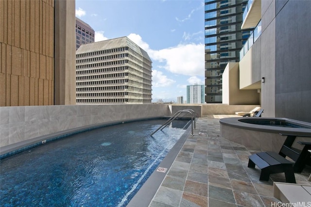 view of swimming pool featuring a view of city and a hot tub