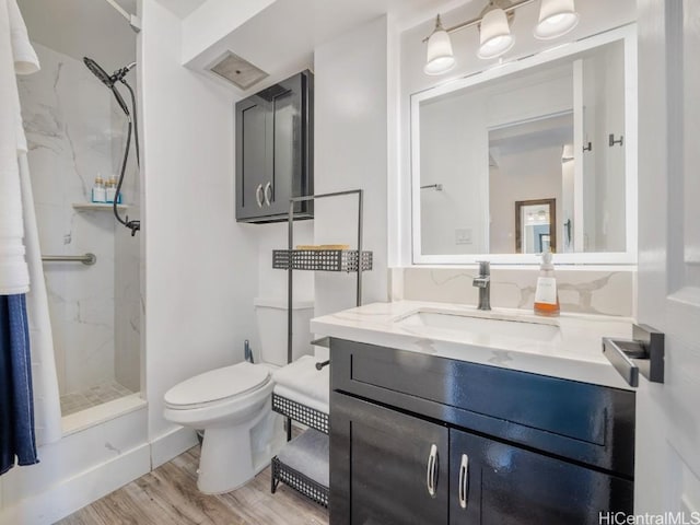 full bath featuring a marble finish shower, vanity, toilet, and wood finished floors