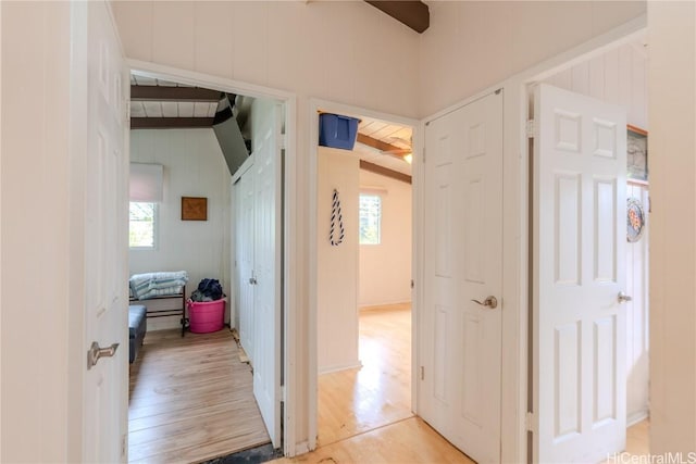 corridor featuring light wood-style flooring and beam ceiling