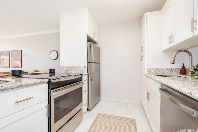 kitchen featuring appliances with stainless steel finishes, a sink, light stone countertops, and white cabinets