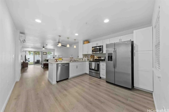 kitchen featuring appliances with stainless steel finishes, open floor plan, decorative light fixtures, light countertops, and white cabinetry