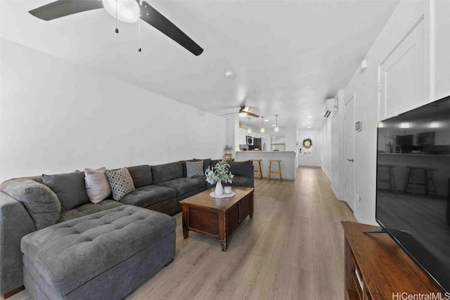 living area featuring light wood-style floors, an AC wall unit, and a ceiling fan