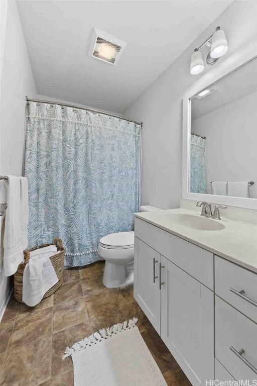 bathroom featuring toilet, vanity, and visible vents