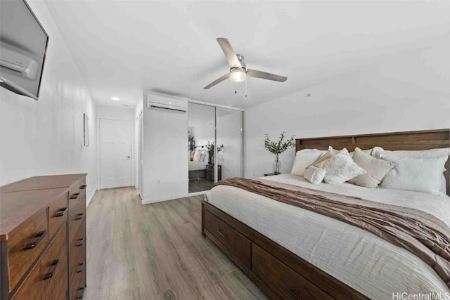 bedroom with light wood finished floors, a closet, a ceiling fan, and a wall mounted air conditioner