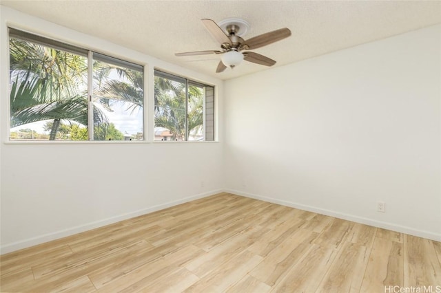 empty room with a ceiling fan, light wood-style flooring, baseboards, and a textured ceiling