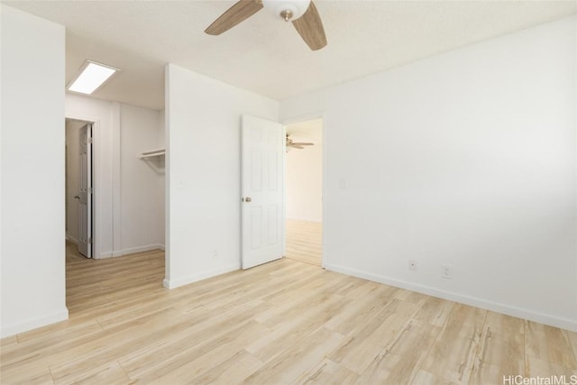 unfurnished bedroom featuring light wood-style flooring, baseboards, and a spacious closet