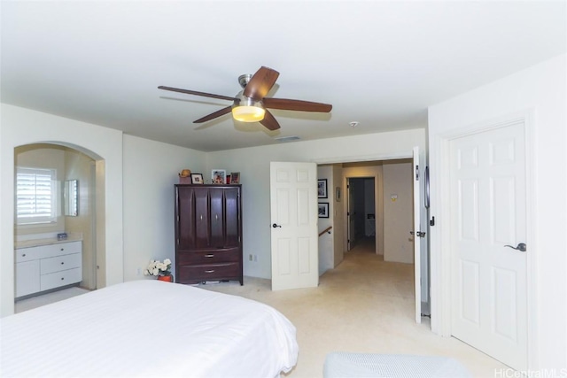 bedroom with visible vents, arched walkways, a ceiling fan, and light colored carpet