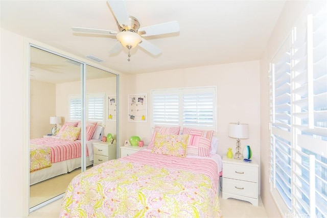 bedroom featuring a closet, visible vents, a ceiling fan, and light colored carpet