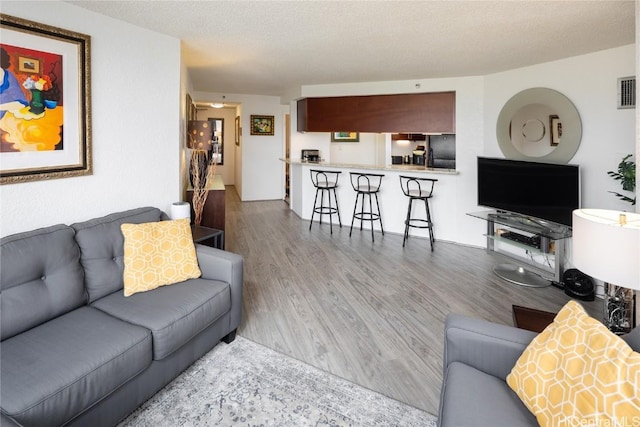 living room with a textured ceiling, wood finished floors, and visible vents