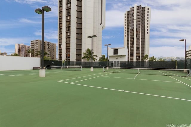 view of tennis court featuring a view of city and fence